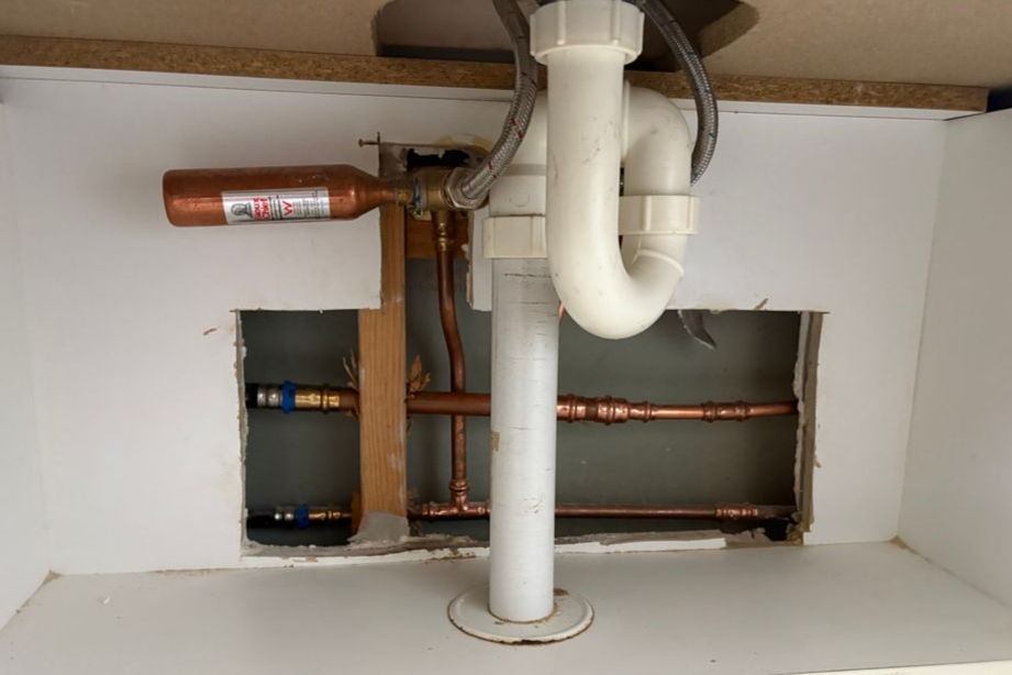 Water Hammer Arrestor Being Installed Under Kitchen Sink